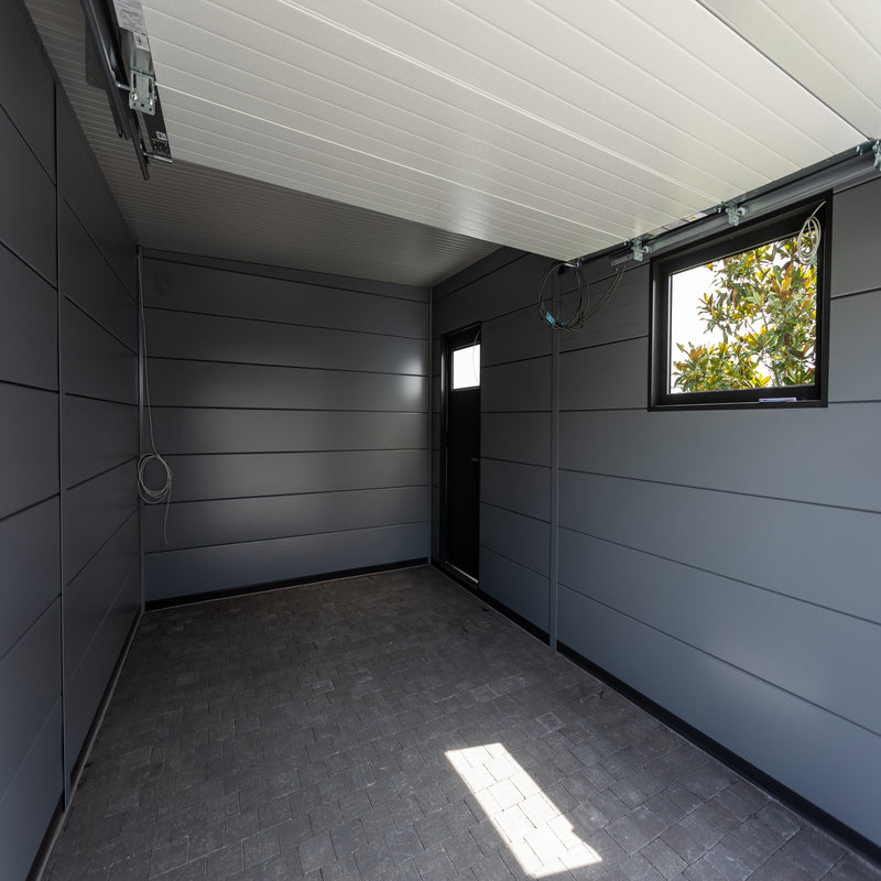 Telluria Sustainable Eleganto Garage in Anthracite. Inside view with Garage door open which can be seen in the roof of the garage. Floor and walls of the inside can be seen with side door and window.