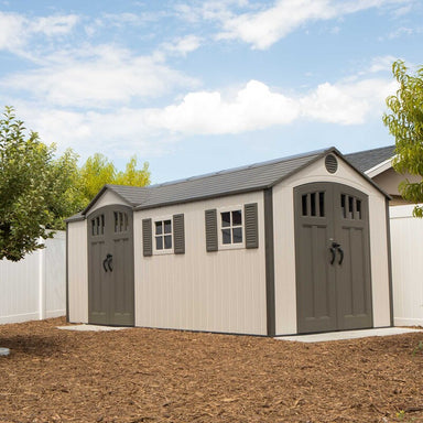 Lifetime 17.5' Cottage Style Plastic Shed,  Dual Entrance. Image of front right outside in garden situ, showing dual entrances, both with double doors and the two front windows with shutters. Covered air vent is above the door on the right end of the building